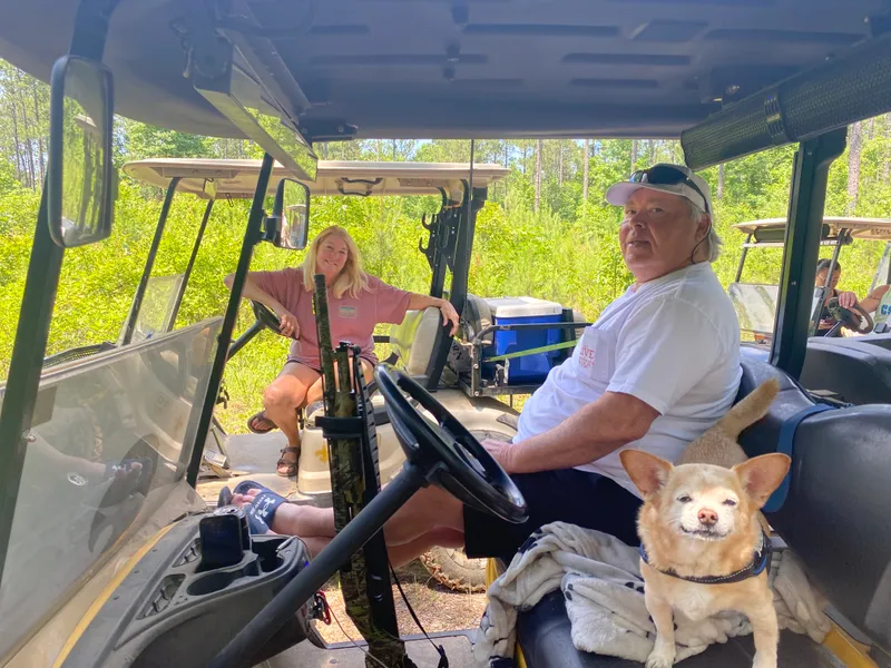 Friends relaxing in parked golf carts with a small dog along for the outing