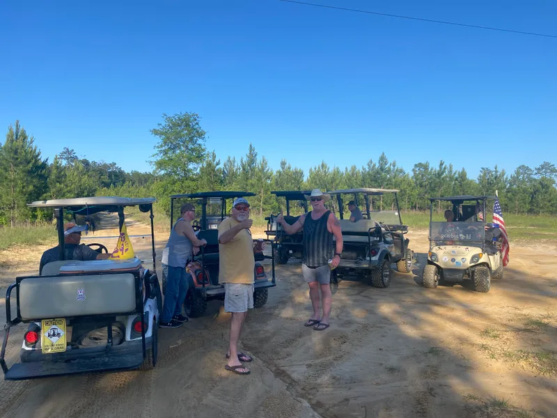 Friends gathered with a line of golf carts under a clear blue sky